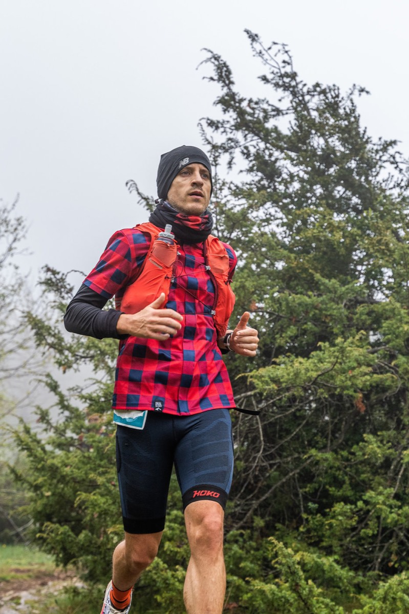 Corredor amb casc i armatura de càmera, corrent per una pista de bosc.