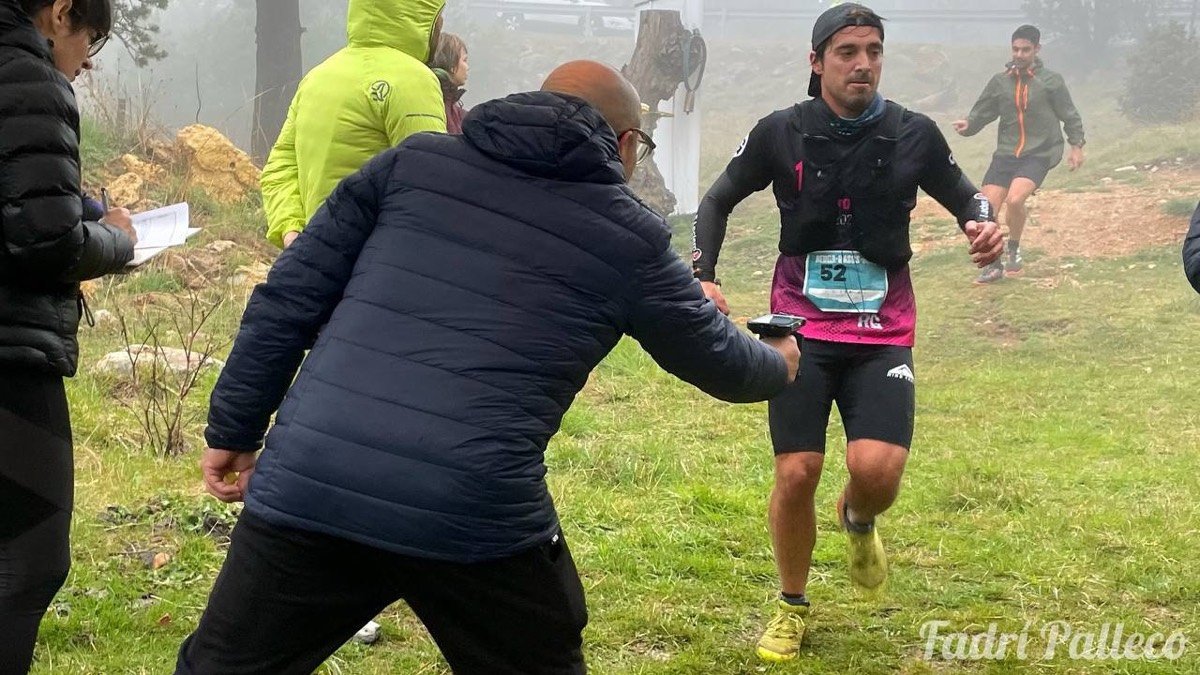 Un corredor abraonat per una altra participant amb un voluntari al costat.