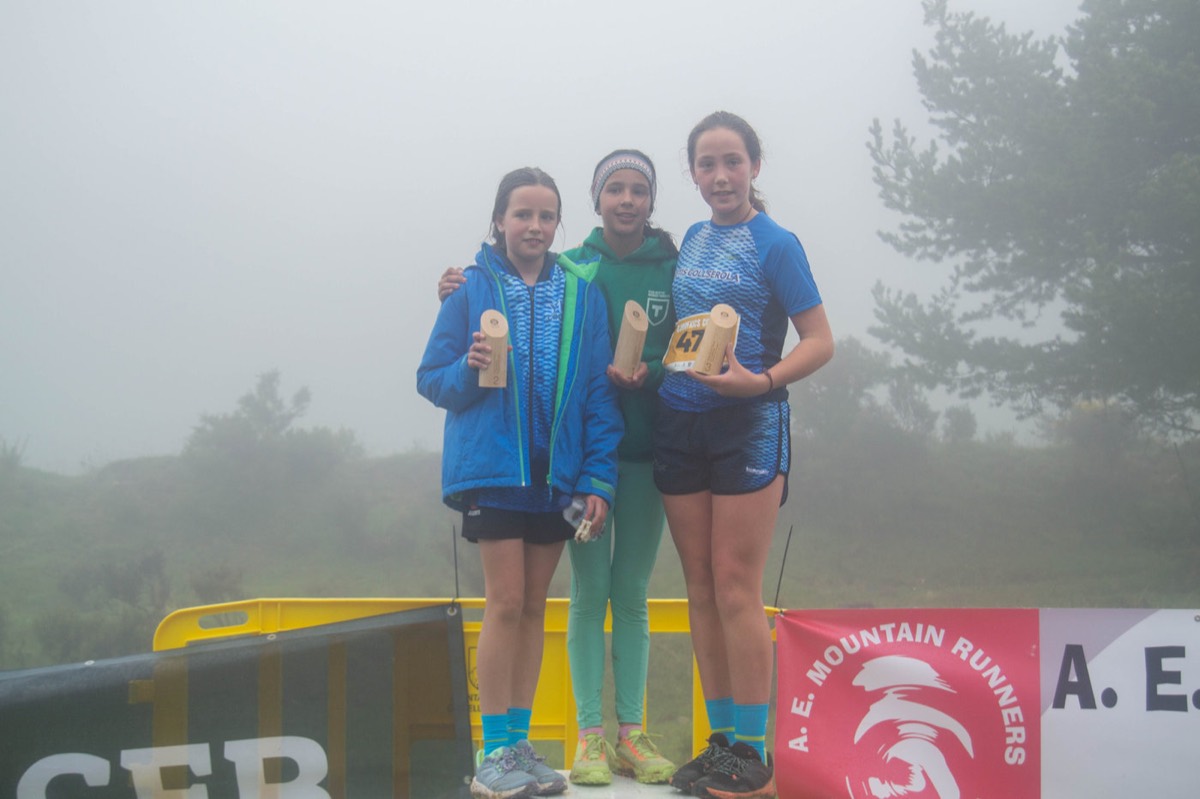 Tres nenes sostenen els seus premis amb boira al fons.