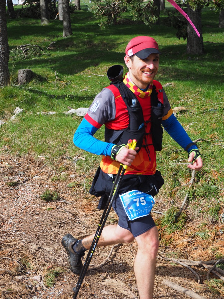 Corredor amb bastons i dorsal 75 pujant entre rocs i gespa.