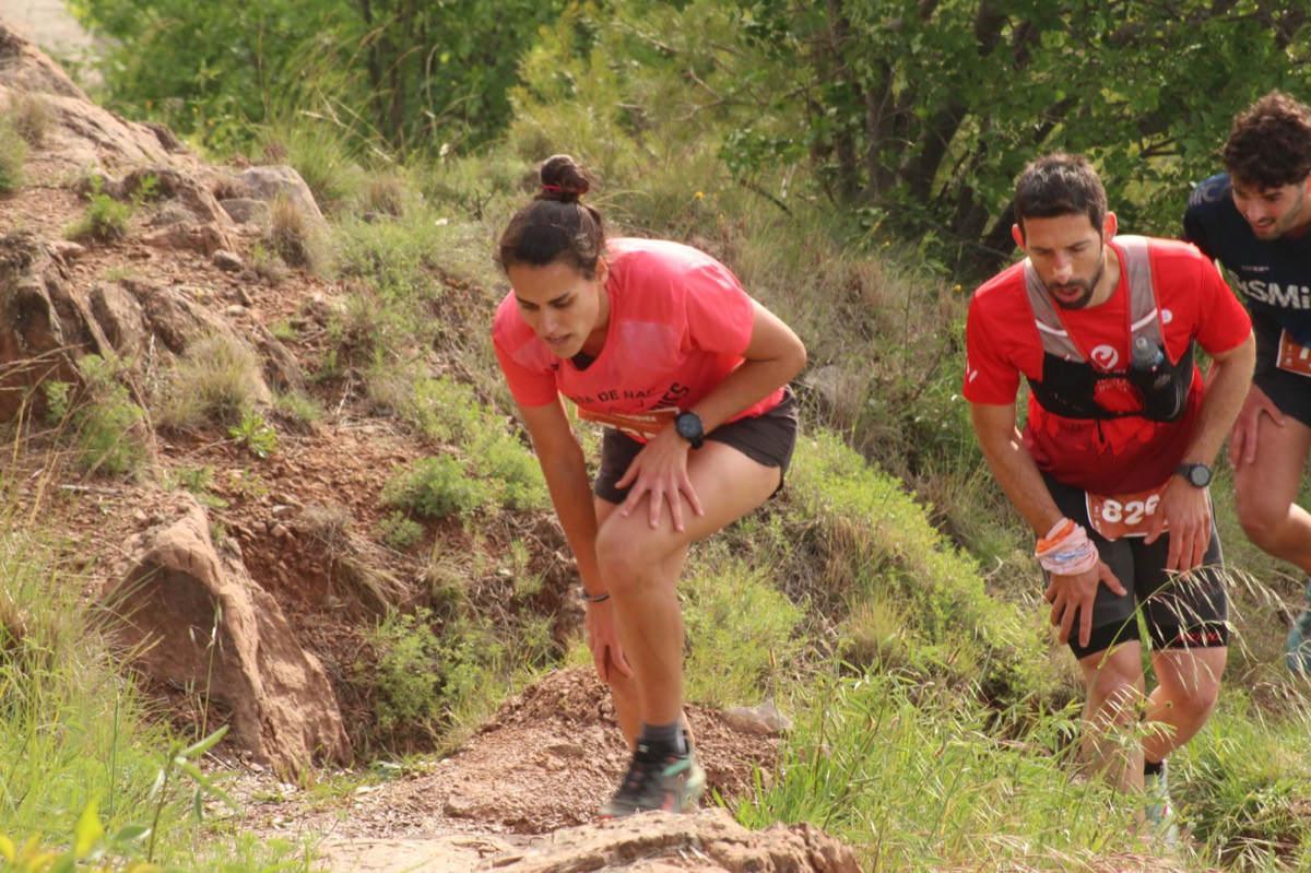Dos corredors pujant amb determinació entre rocs i matollar.